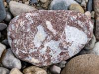 Rotbrauner Stein mit vielen verschiedengroßen hellen Flecken